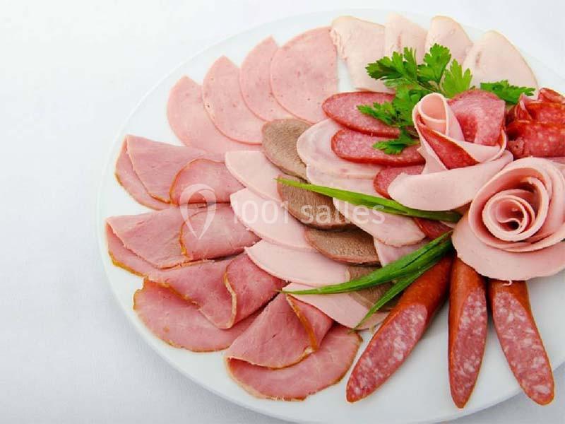 Assortiment de charcuteries variées disposées sur une assiette blanche, décorée de persil et d'oignons verts.