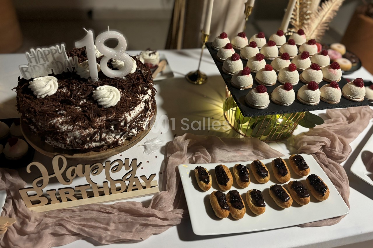 Table décorée pour un 18e anniversaire avec gâteau au chocolat, éclairs et mignardises garnies de framboises.