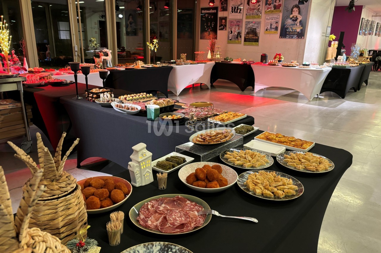 Buffet varié avec des plats salés et sucrés disposés sur des tables dans une salle éclairée.