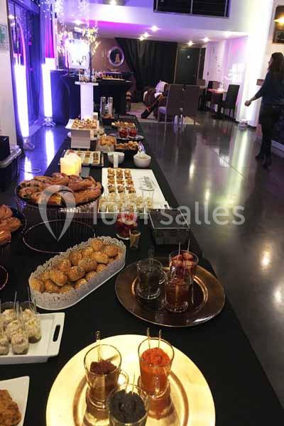 Buffet varié avec amuse-bouches, viennoiseries et boissons, disposé sur une table dans une salle lumineuse.