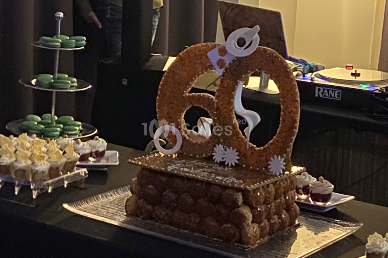 Pièce montée en choux décorée pour un 60e anniversaire, entourée de macarons et desserts sur une table festive.