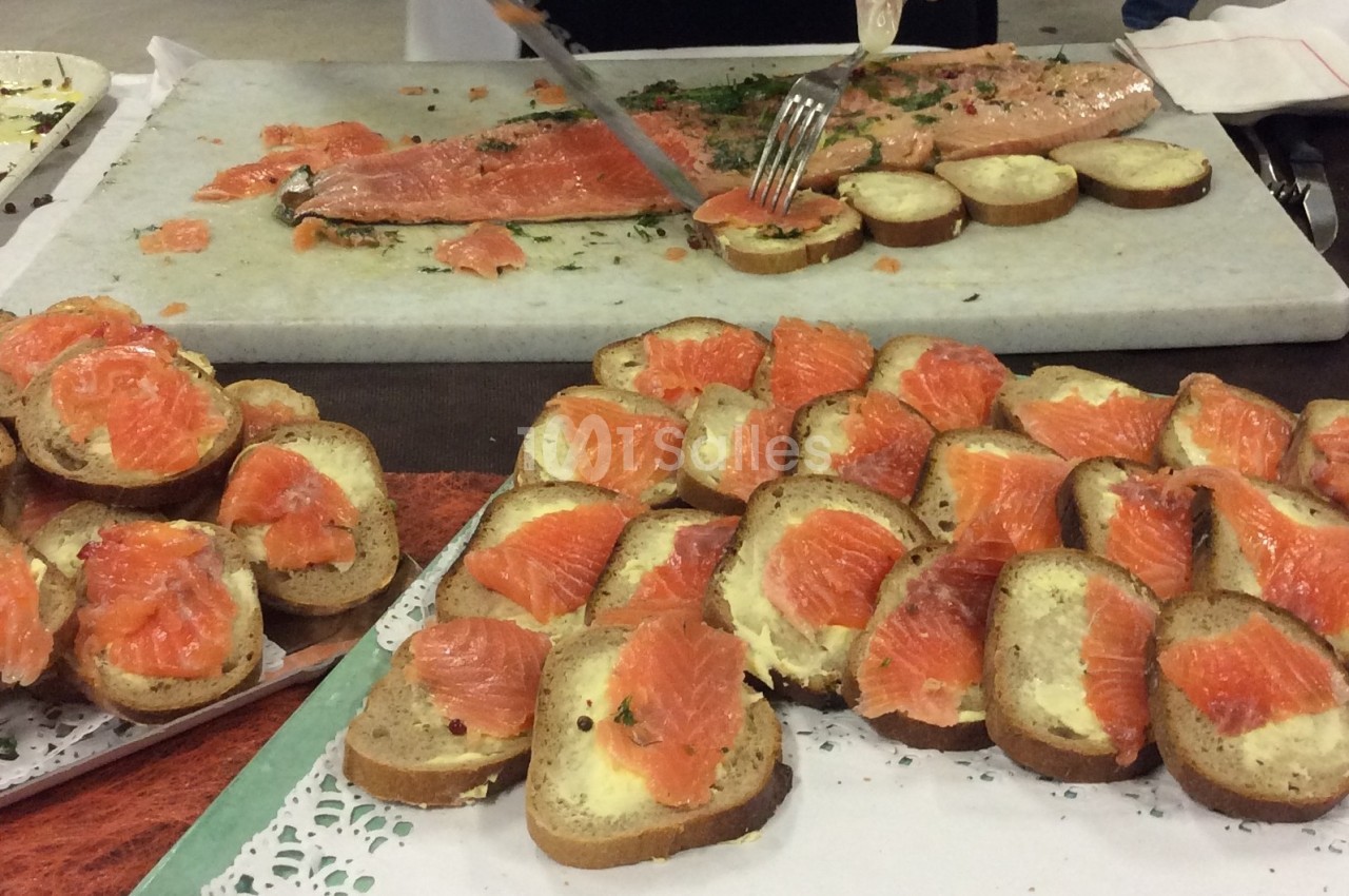 Tranches de saumon fumé sur des tartines de pain beurré, disposées sur une table lors d'une préparation culinaire.