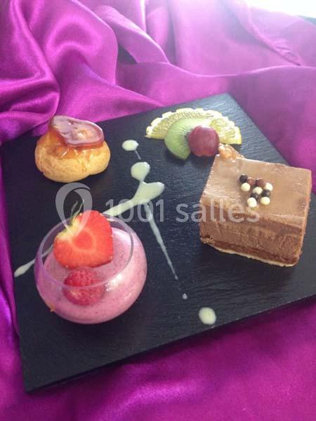 Assortiment de desserts élégants sur une ardoise noire, comprenant mousse, gâteau au chocolat et fruits frais.