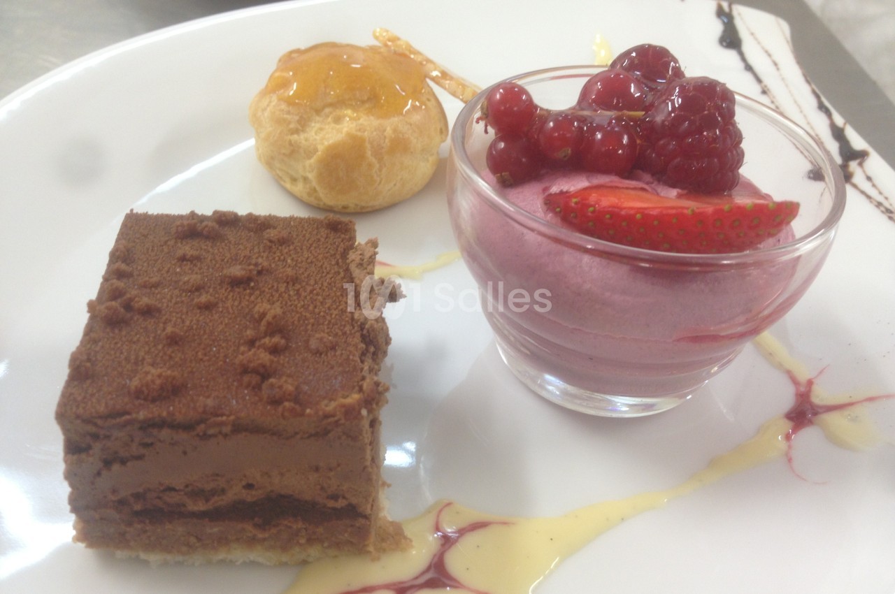 Assiette de desserts composée d'un gâteau au chocolat, d'une mousse aux fruits rouges et d'une chouquette glacée.