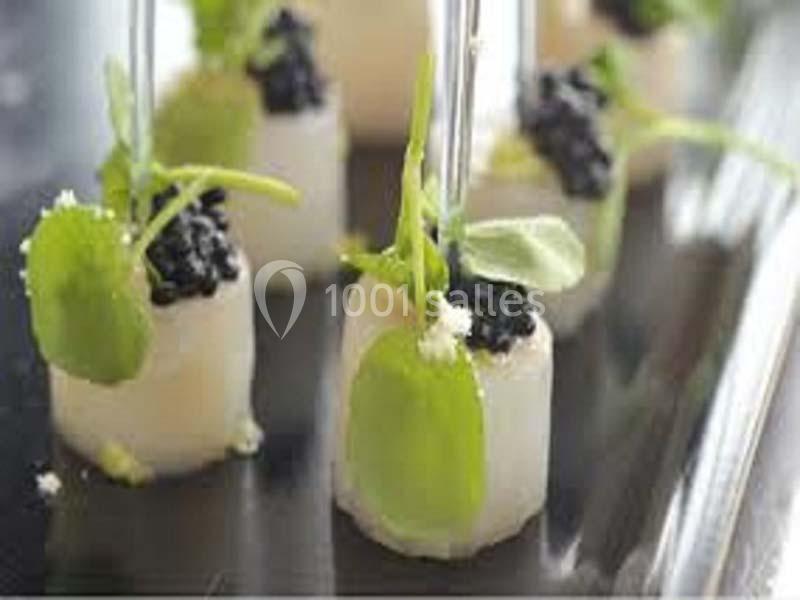 Bouchées élégantes de radis blanc garnies de caviar noir et de feuilles vertes, présentées sur un plateau.