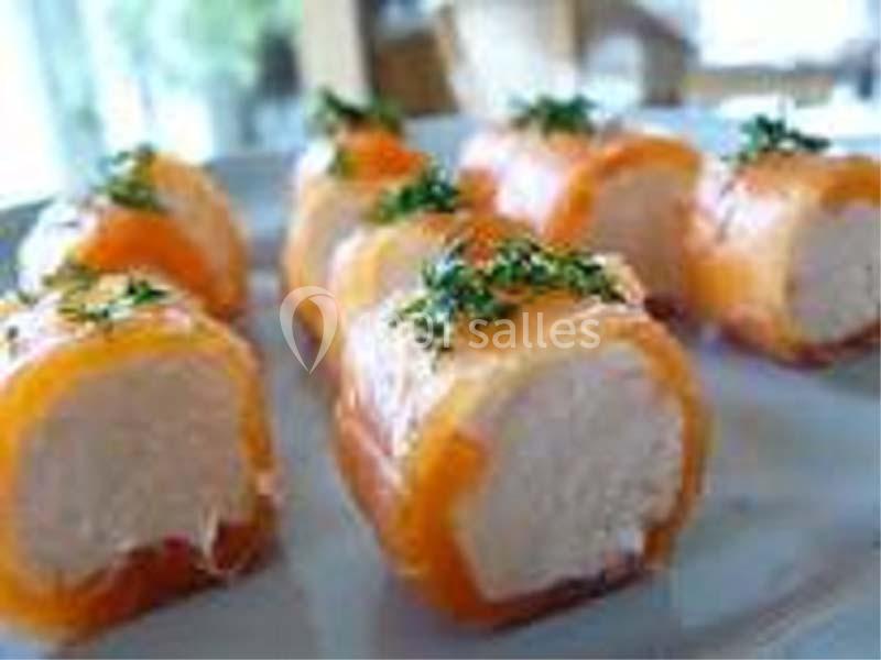 Roulés de saumon fumé garnis de fromage frais, décorés de brins d'herbes fraîches sur une assiette blanche.