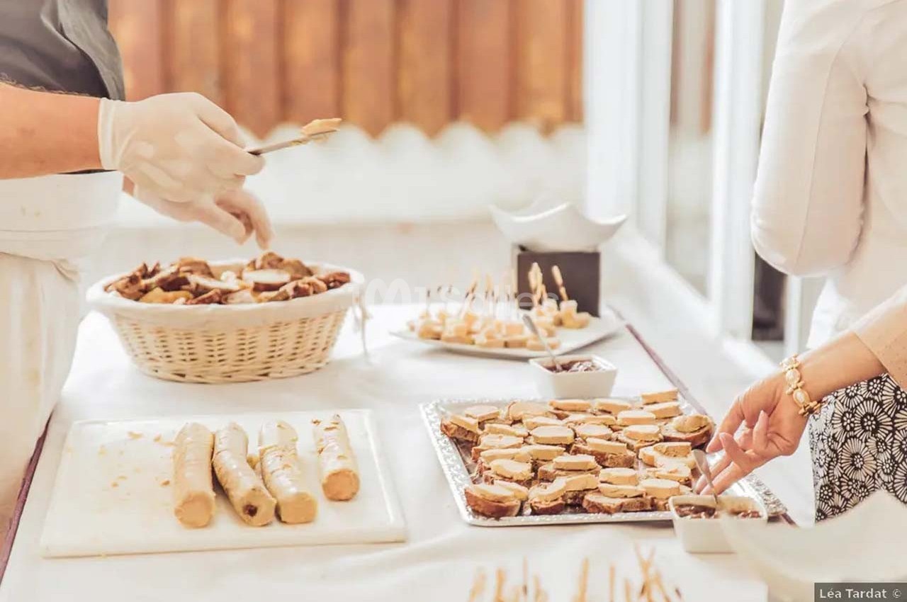 Personnes préparant et disposant des amuse-bouches sur une table garnie de plateaux et d'un panier de pain.