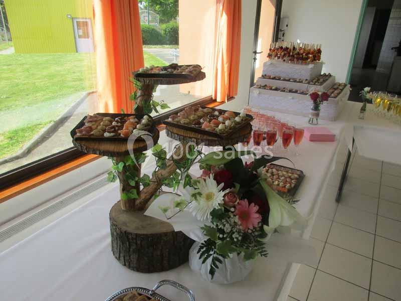 Table de réception avec présentoirs de mignardises, bouquet de fleurs et verres de boissons alignés.