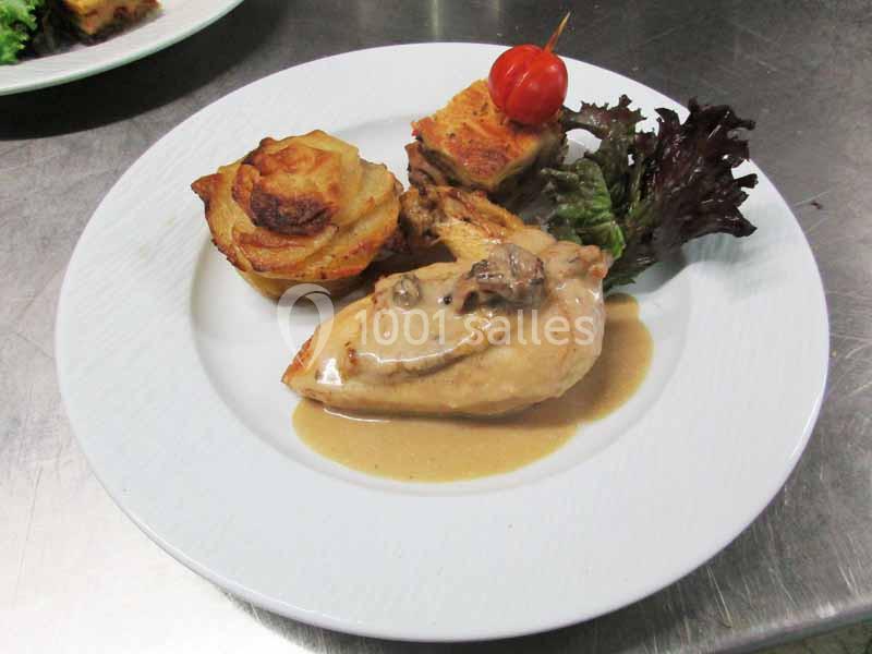 Assiette composée de poulet sauce crème, gratin de pommes de terre, légumes et salade, servie sur une table en inox.
