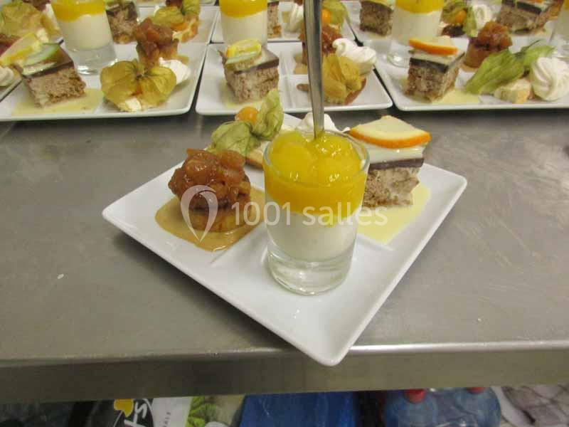 Assiette de desserts variés comprenant une verrine, un gâteau et des fruits, présentée sur une table en inox.