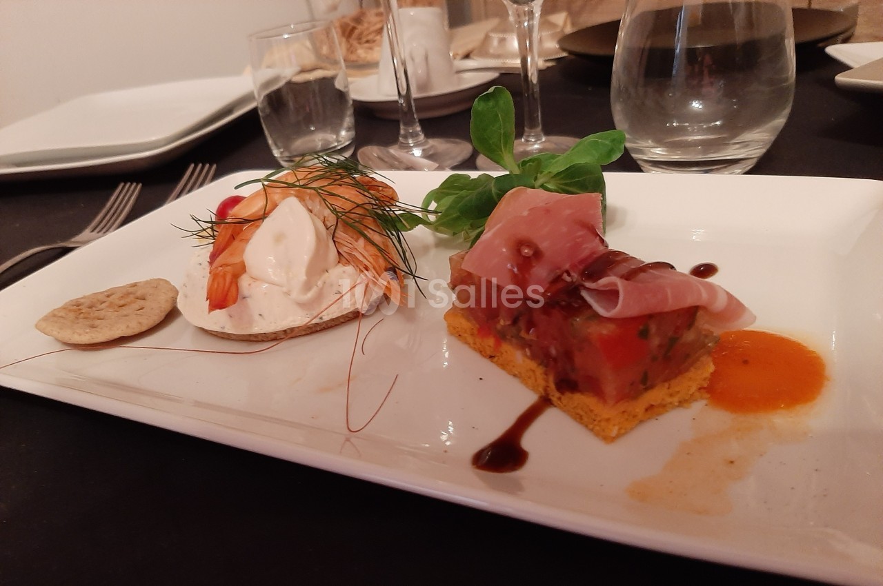 Assiette gastronomique avec tartine aux crevettes, cube de légumes sur biscuit salé et sauce, décorée de verdure.