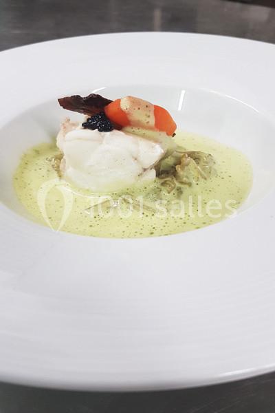 Plat gastronomique avec filet de poisson, légumes, caviar et sauce verte, présenté dans une assiette blanche.
