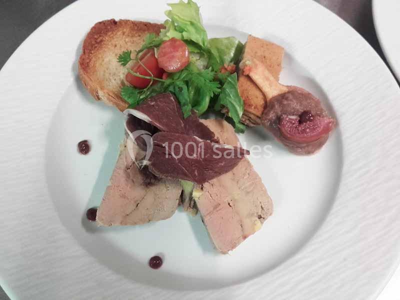 Assiette composée de foie gras, toast, salade verte, tomates cerises et figue, présentée sur une assiette blanche.