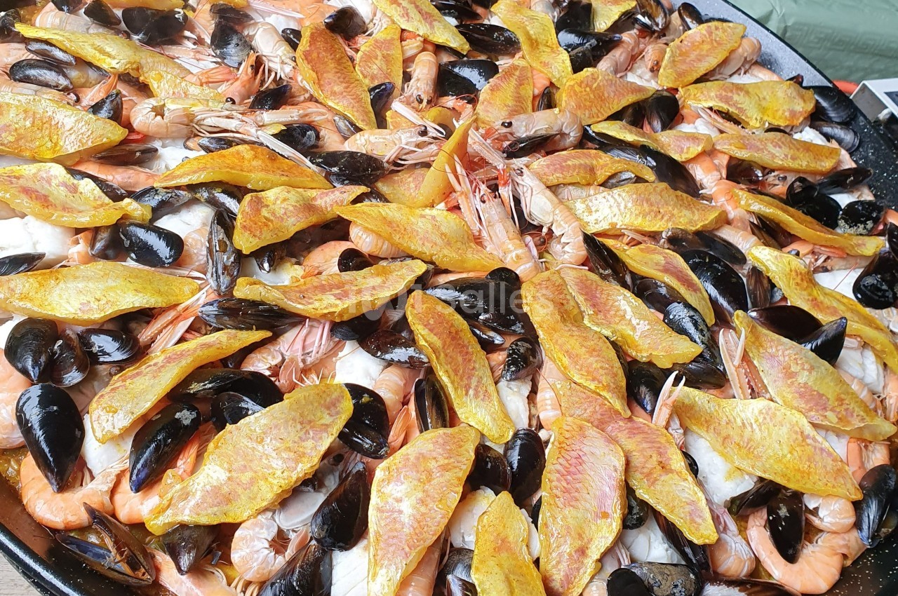 Plat de paella garni de crevettes, moules, filets de rouget et riz safrané.