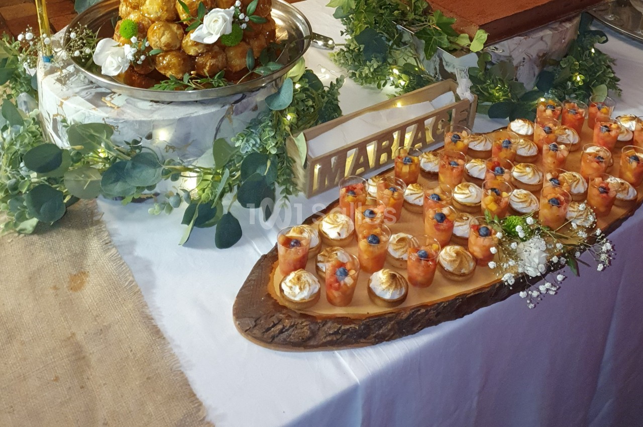 Buffet de desserts avec verrines colorées, pièce montée et décoration florale sur une table de mariage.