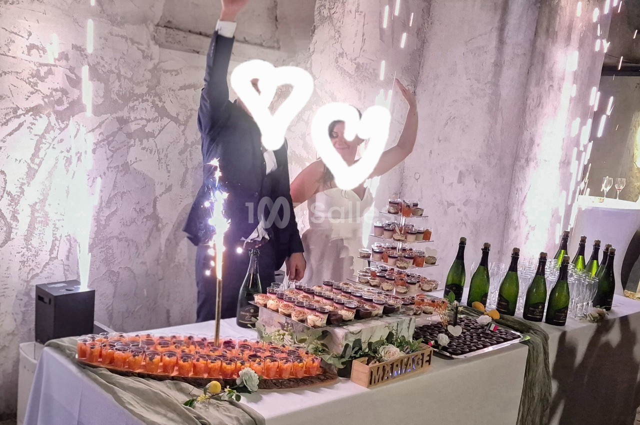 Un couple debout derrière une table de desserts et boissons, décorée pour une réception festive avec des étincelles.