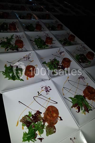 Assiettes dressées avec tartares de viande, salades fraîches et traits de sauce, alignées sur une table sombre.