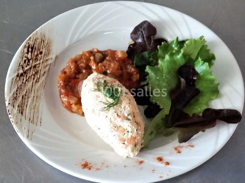 Assiette composée d'une quenelle de poisson, ratatouille, feuilles de salade et décoration de sauce sur le bord.