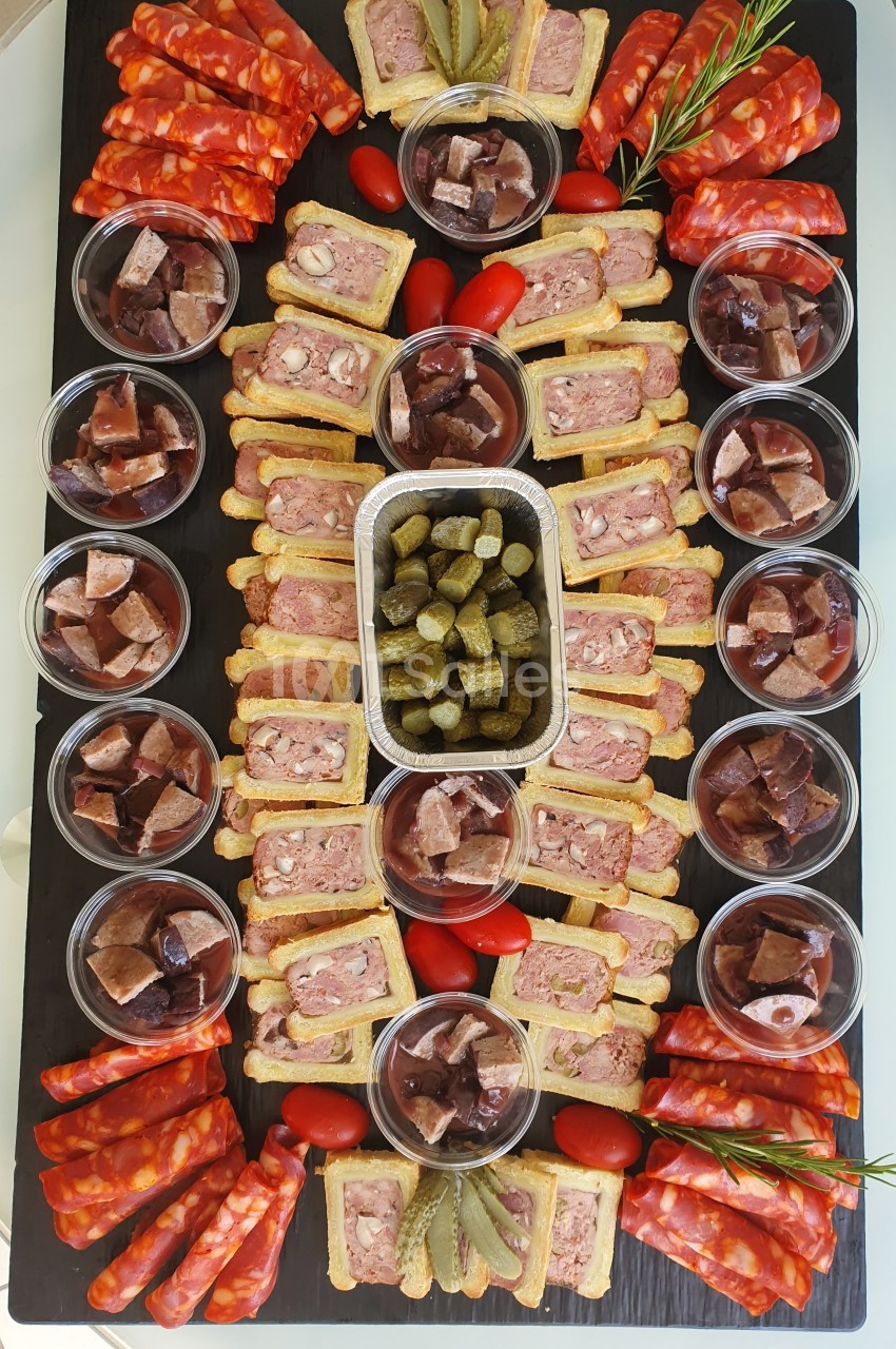 Plateau de charcuterie avec pâtés en croûte, cornichons, chorizo, tomates cerises et verrines de gelée de viande.