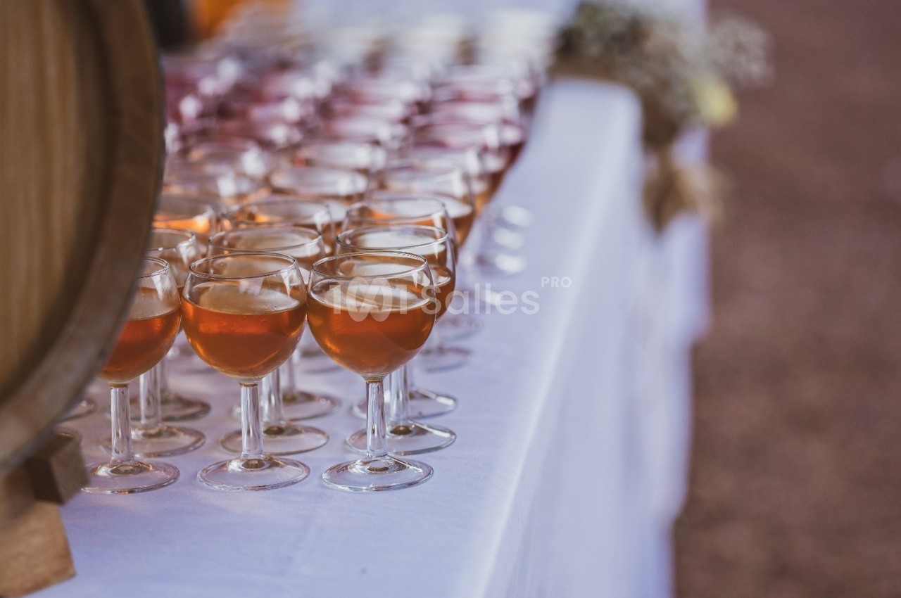 Verres de vin rosé alignés sur une table blanche lors d'un événement en extérieur.