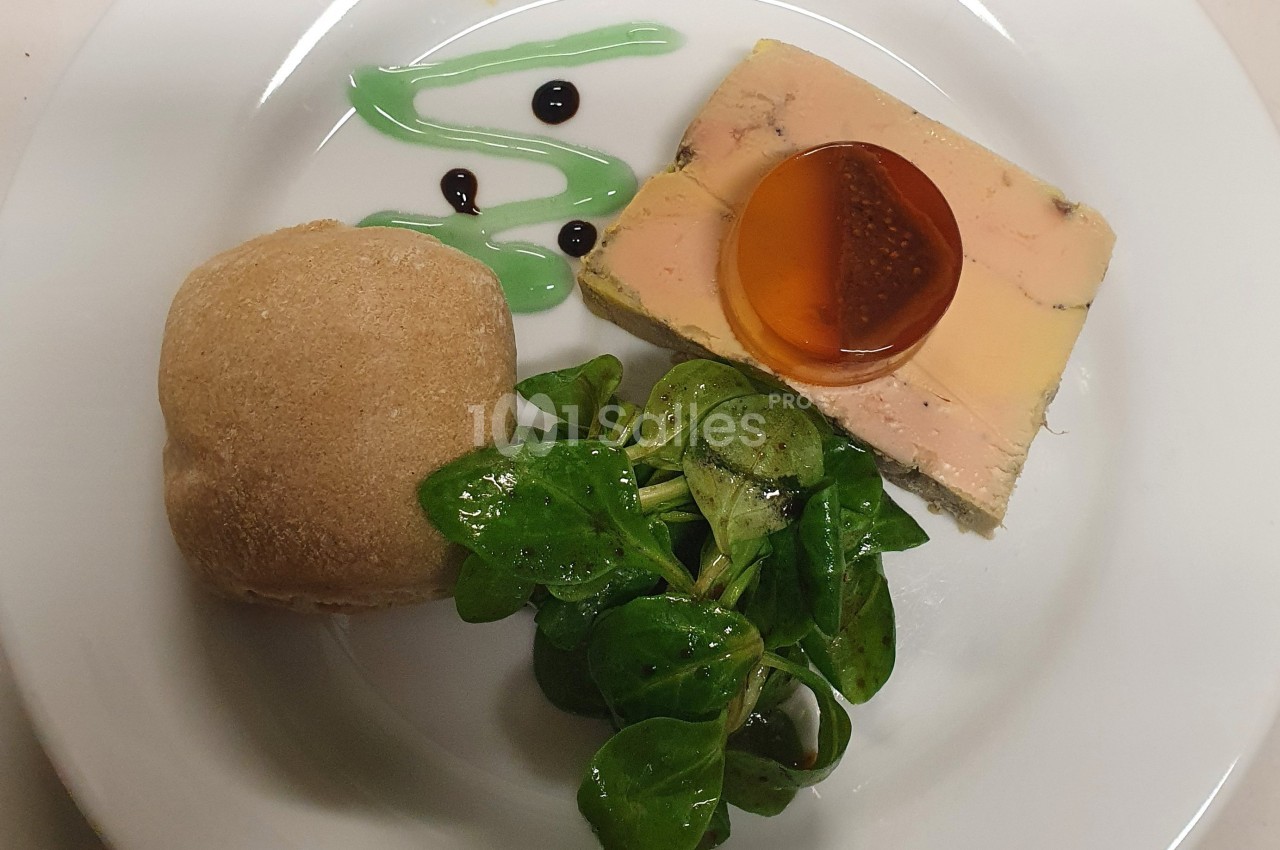 Assiette composée de foie gras avec gelée, salade verte, pain et décorations de sauce.