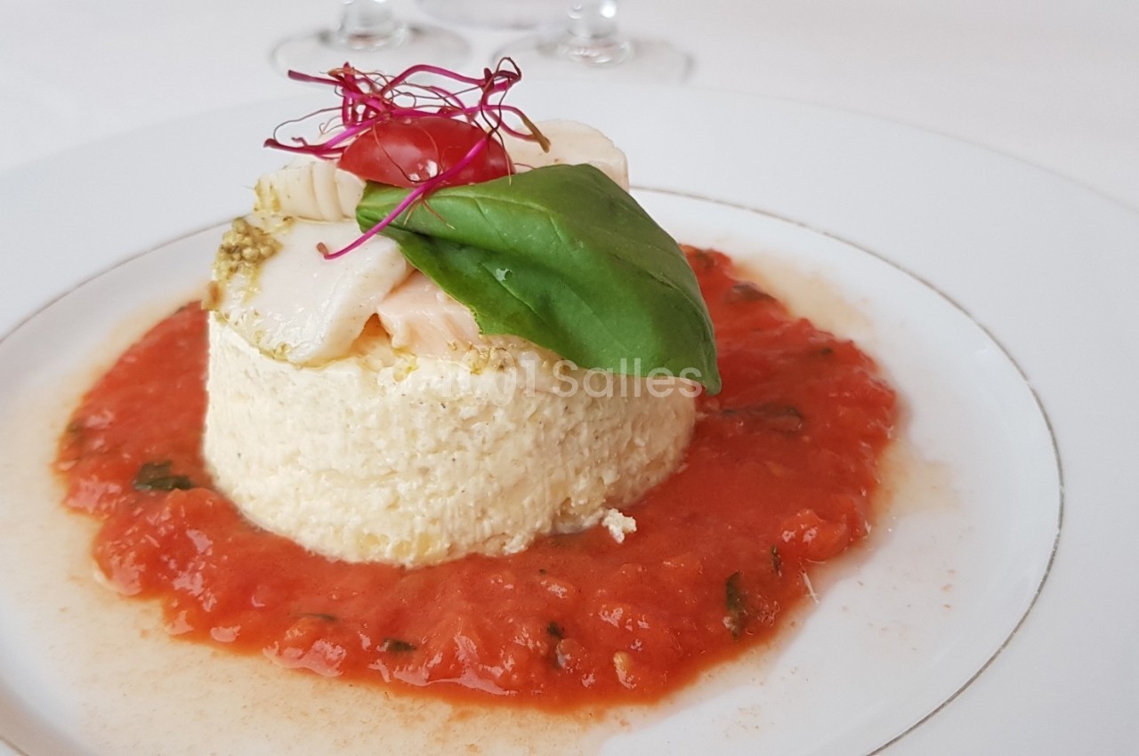 Assiette de flan salé garni de basilic, tomate cerise et pousses, entouré de sauce tomate.