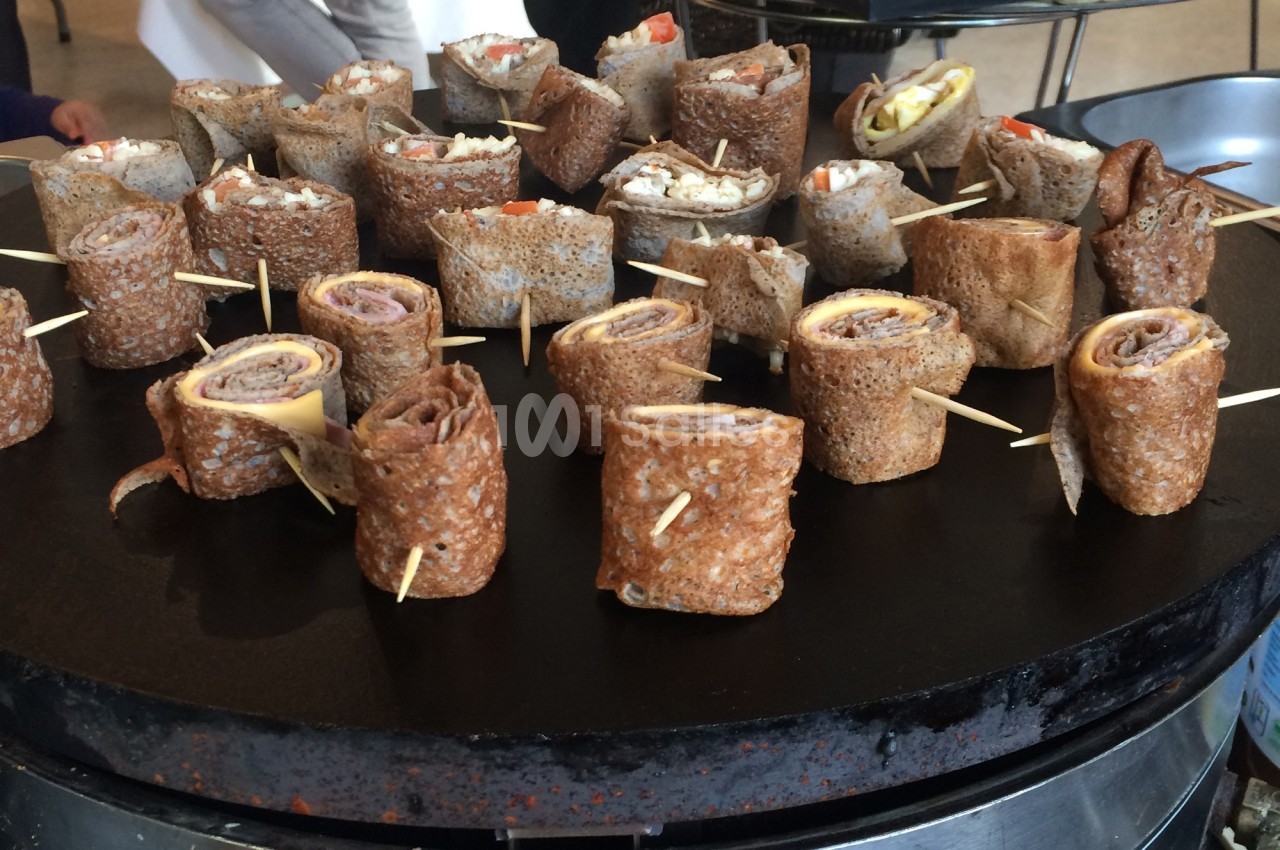 Assortiment de roulés de galettes de sarrasin garnis, présentés sur une plaque de cuisson.