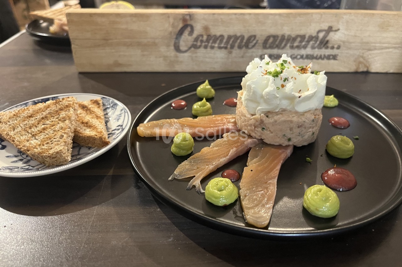 Assiette avec tartare de poisson, tranches de saumon fumé, crème, purées colorées et toasts grillés à côté.