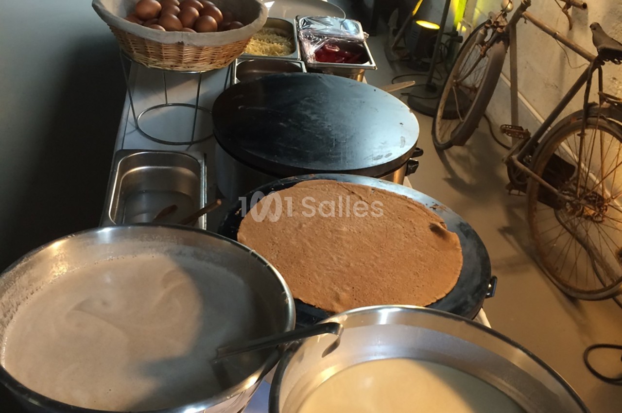 Préparation de crêpes sur des plaques chauffantes avec des ingrédients disposés sur une table à proximité.