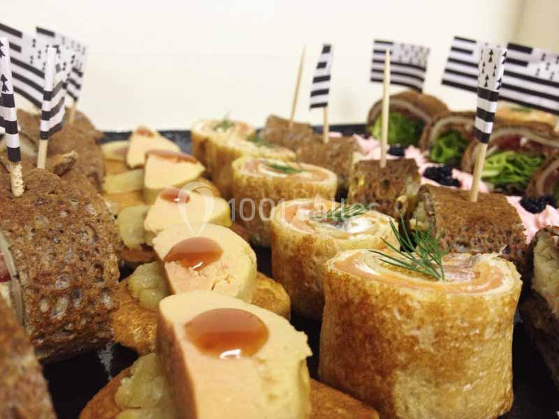 Assortiment de bouchées apéritives, dont des roulés de crêpes garnis et des toasts décorés de drapeaux bretons.
