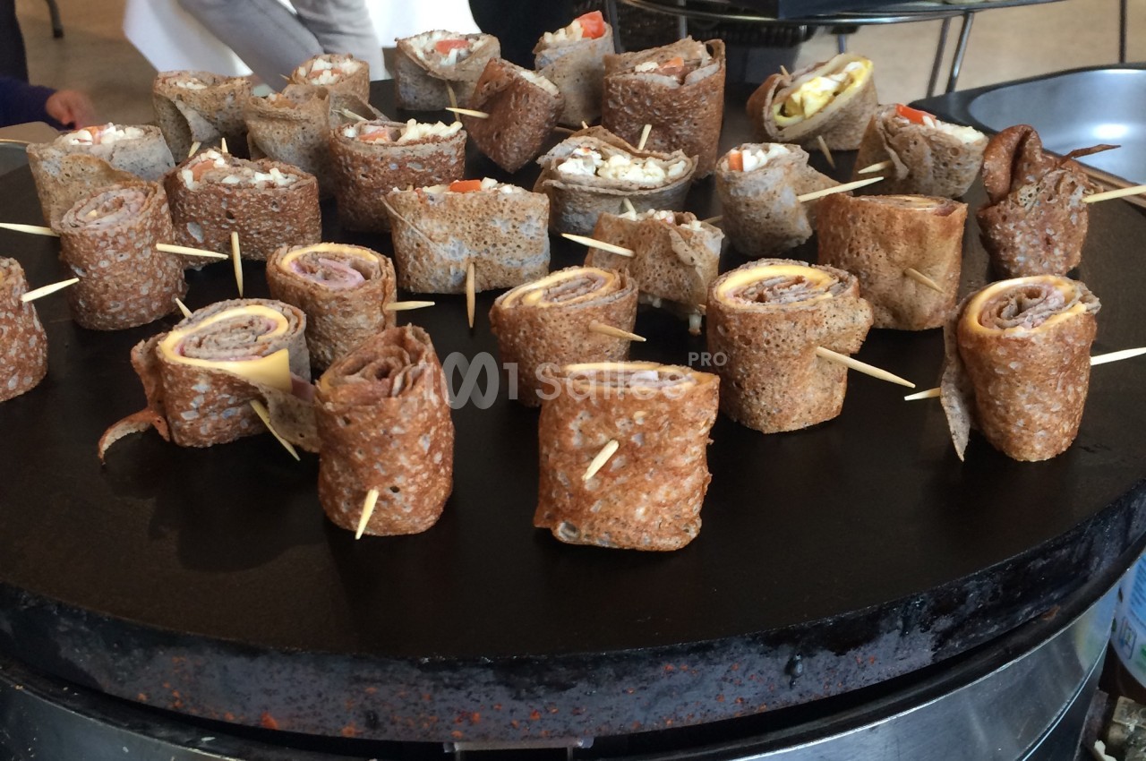 Assortiment de roulés de galettes de sarrasin garnis, présentés sur une plaque de cuisson.