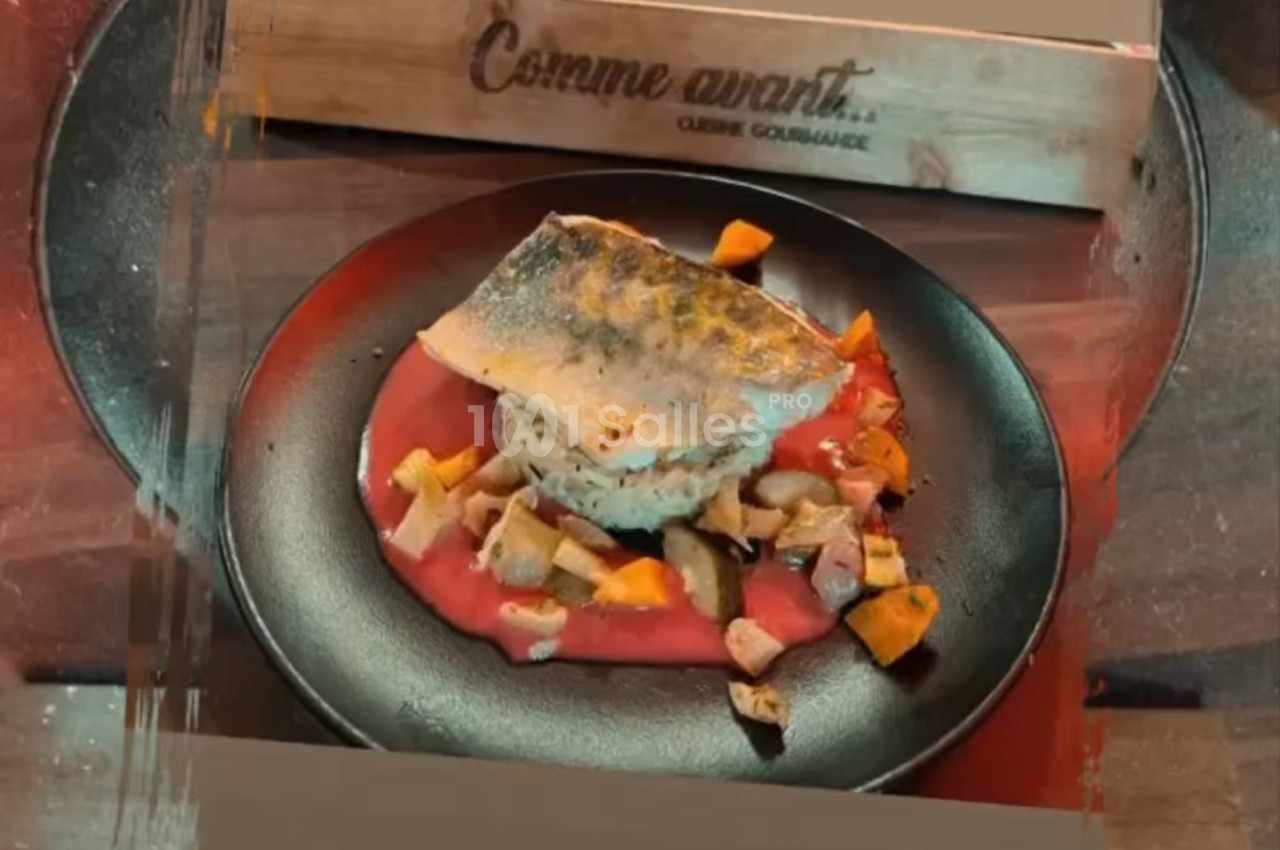 Filet de poisson servi sur une purée rose avec des morceaux de légumes dans une assiette noire.