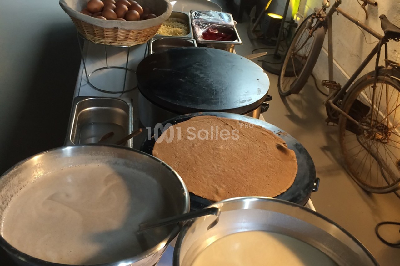 Préparation de crêpes sur des plaques chauffantes avec des ingrédients disposés sur une table à proximité.