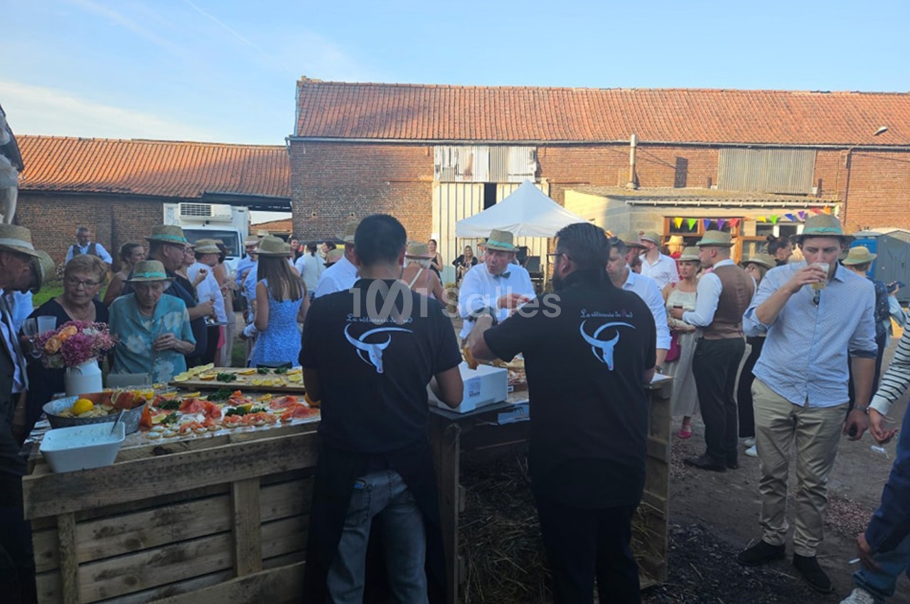 Un stand de nourriture en plein air avec des serveurs et des invités rassemblés dans une ambiance festive rurale.