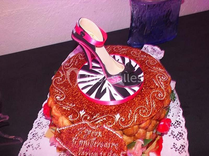 Gâteau décoré d'une chaussure à talon en sucre, posé sur une table avec des détails de crème et caramel.