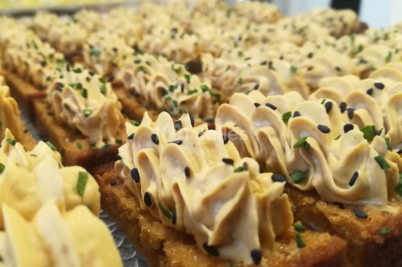 Tranches de pain grillé garnies de mousse crémeuse, parsemées de graines de sésame noir et de ciboulette.