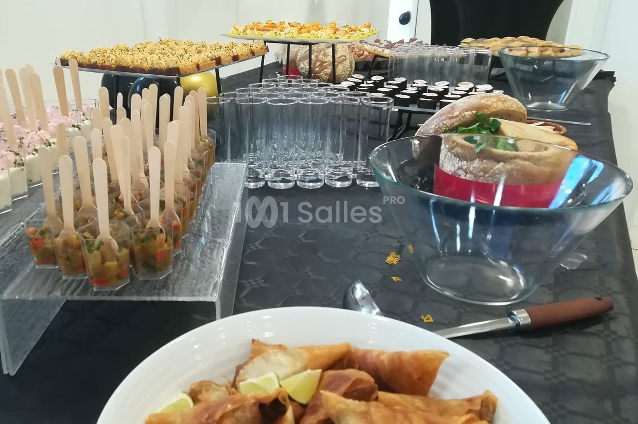 Buffet varié avec verrines, amuse-bouches, pains et pâtisseries disposés sur une table noire.