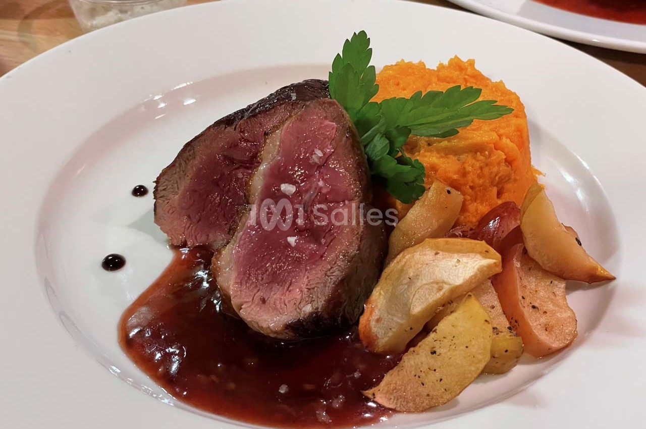 Assiette contenant un filet de viande saignante, purée de patate douce, pommes rôties et sauce au vin rouge.