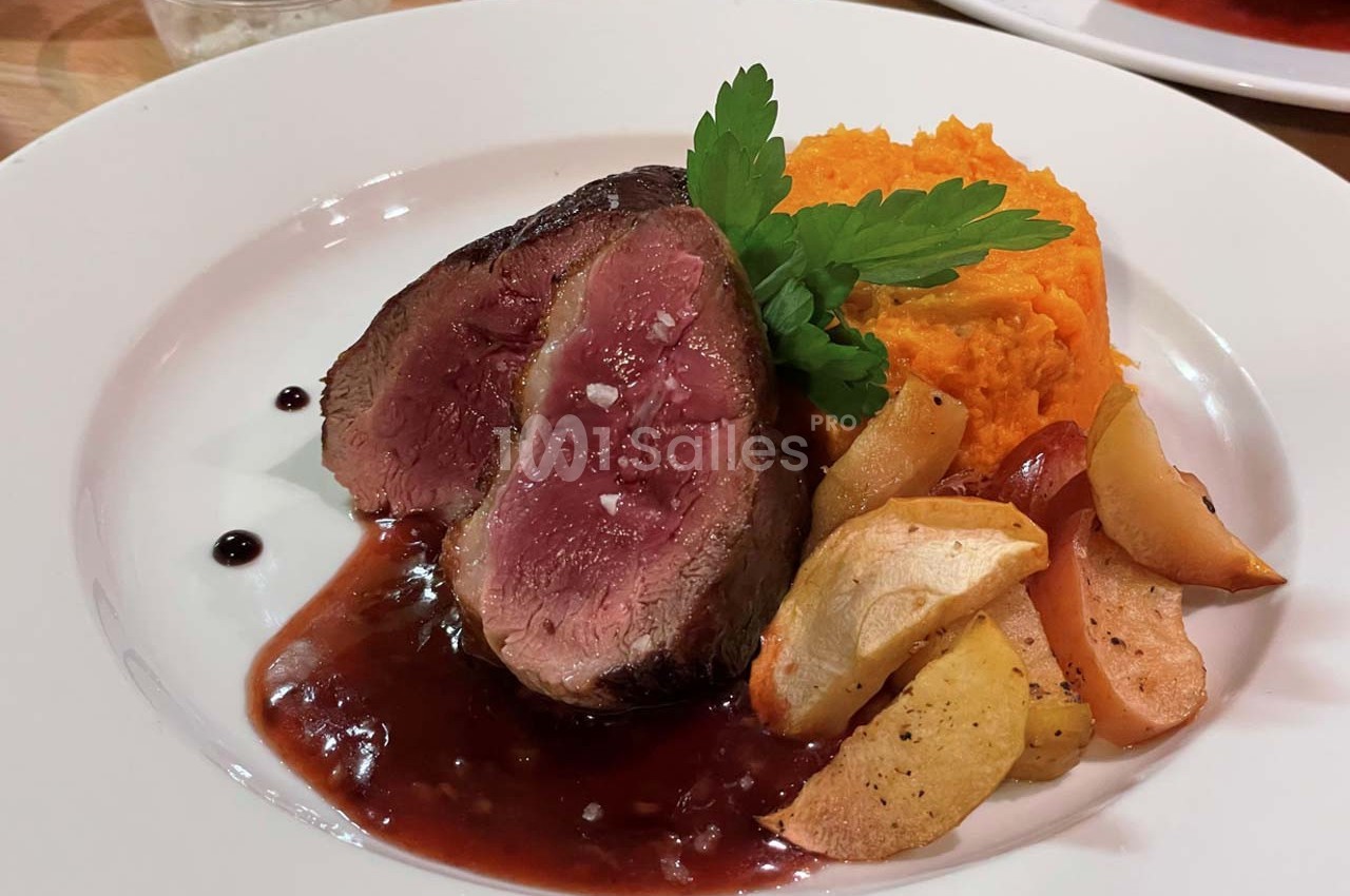 Assiette contenant un filet de viande saignante, purée de patate douce, pommes rôties et sauce au vin rouge.