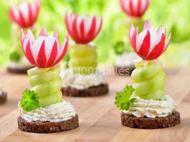 Radis sculptés en forme de fleurs sur des spirales de concombre, posés sur des toasts garnis de crème et de persil.