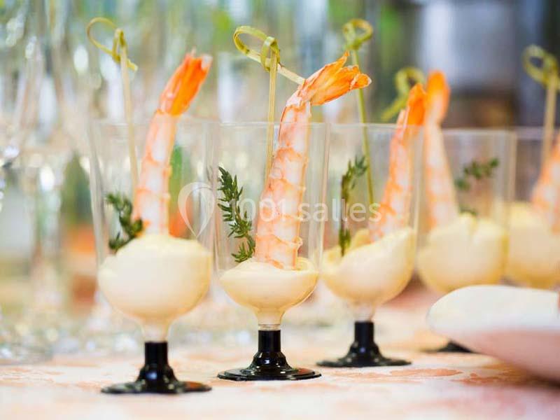 Crevettes dressées sur des verrines de sauce, décorées de brins de persil et servies en apéritif.