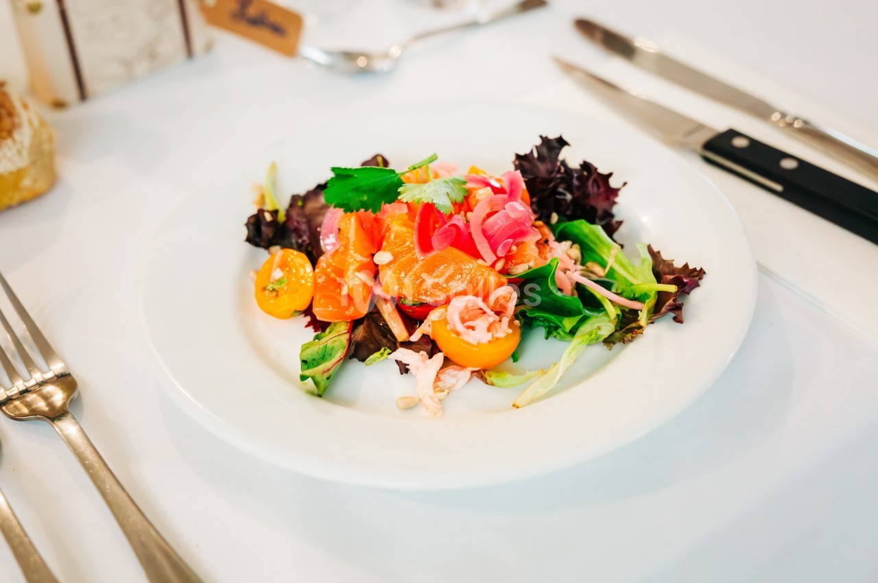 Assiette de salade colorée avec tomates cerises, feuilles de salade, légumes marinés et herbes fraîches.