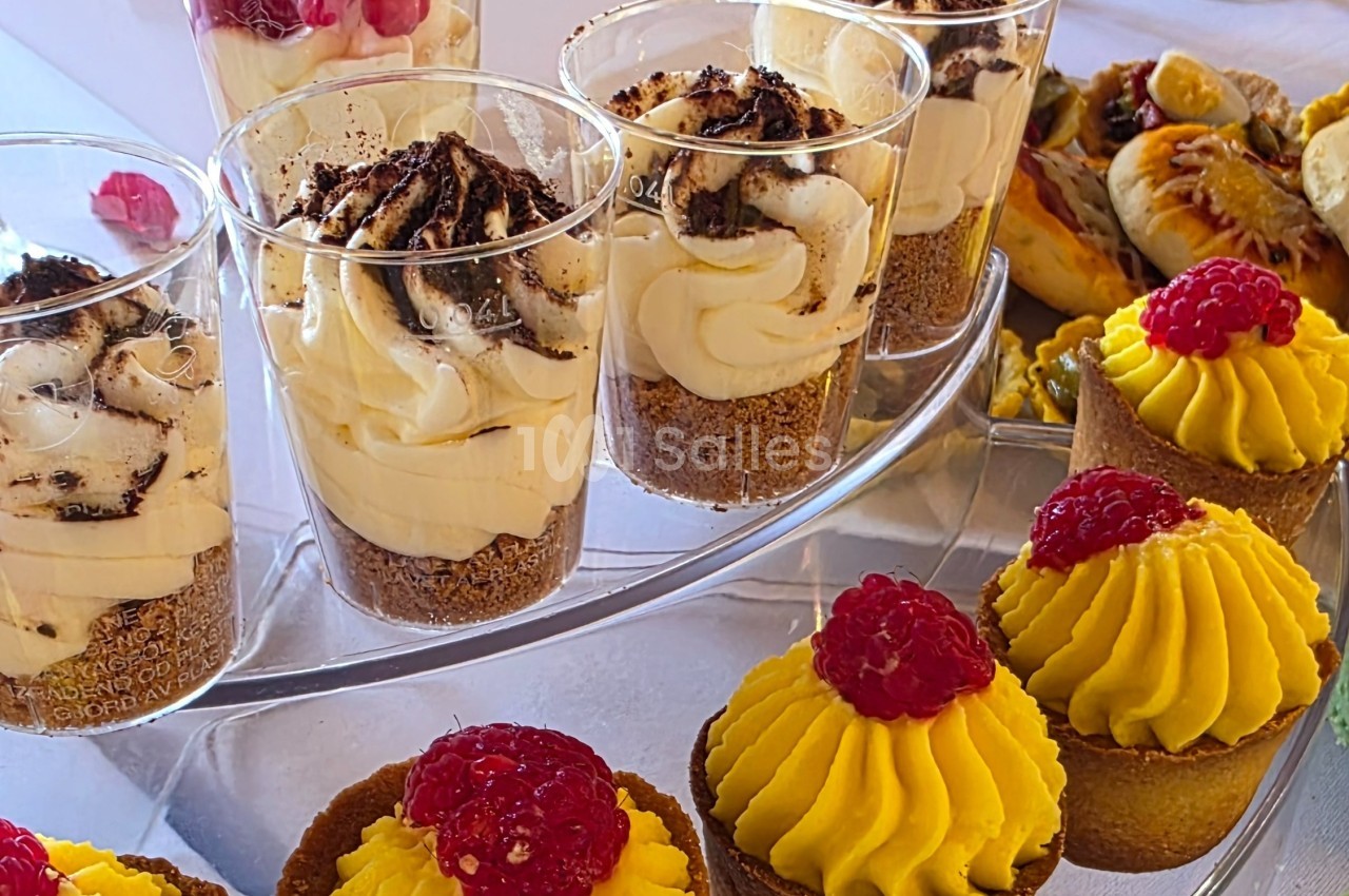 Desserts variés présentés sur un plateau, incluant verrines à la crème et tartelettes garnies de framboises.