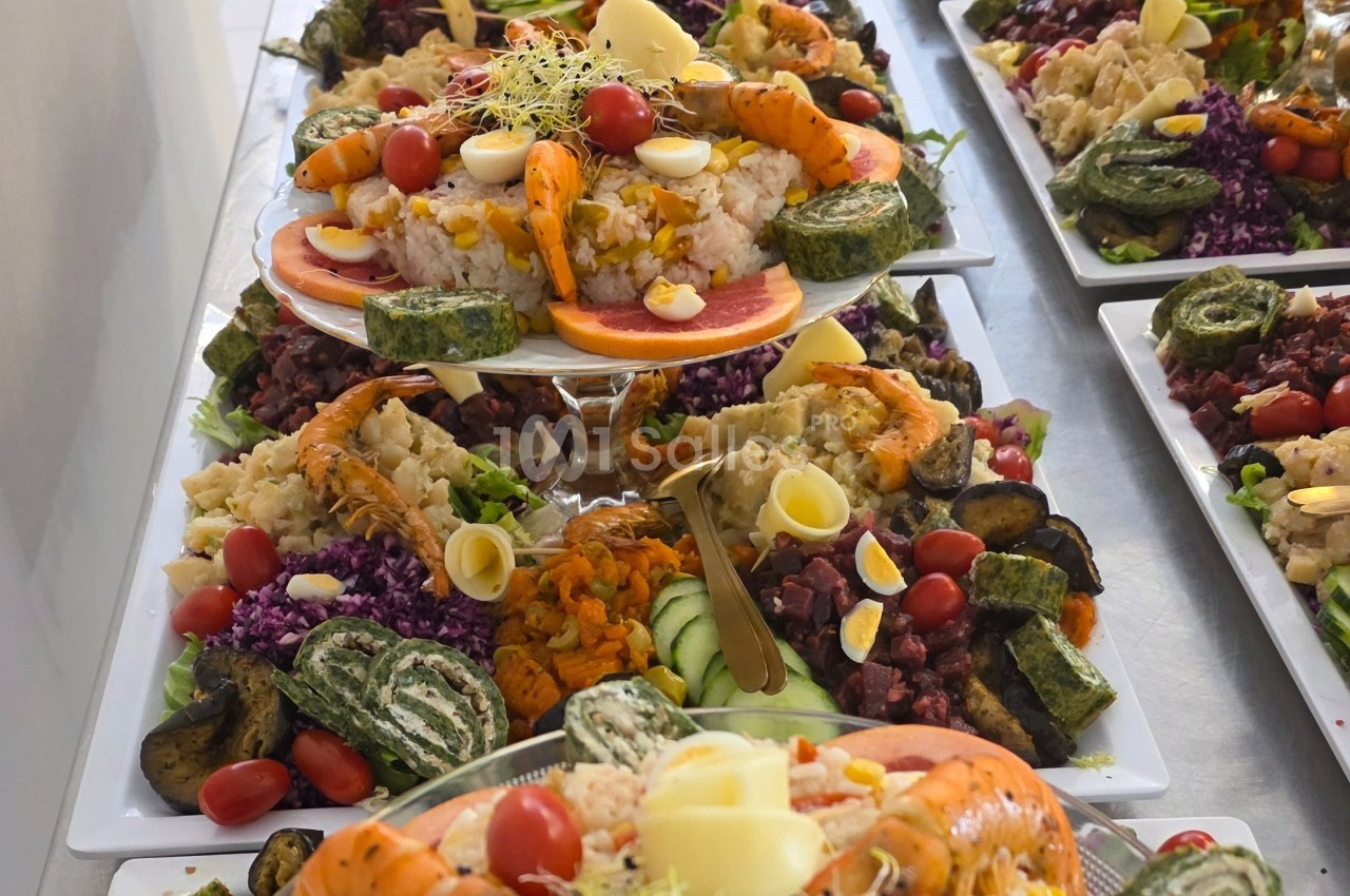 Plateaux garnis de fruits de mer, légumes, œufs durs, roulés d'épinards et garnitures variées sur une table.