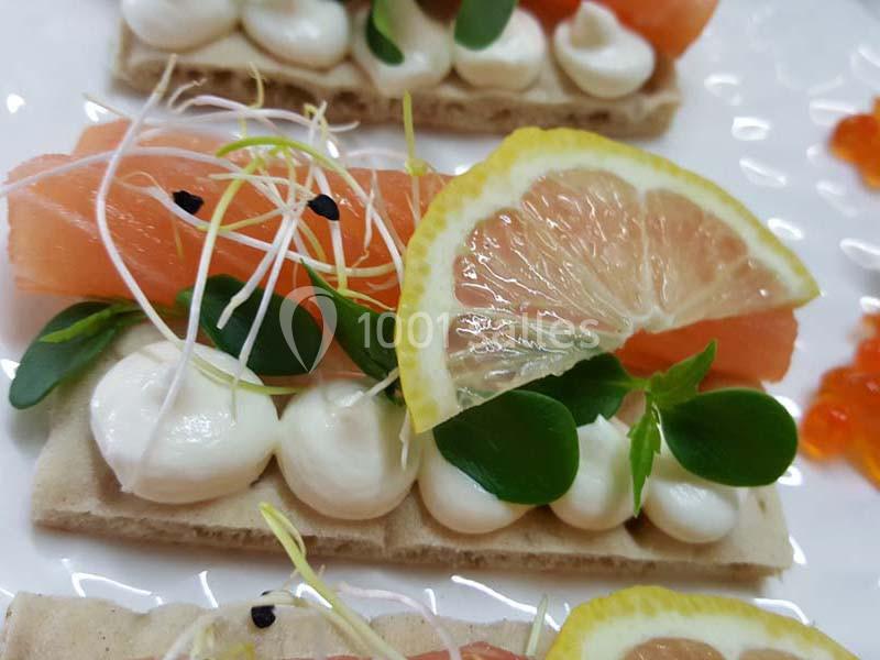 Crackers garnis de fromage frais, saumon fumé, pousses, graines et tranche de citron.