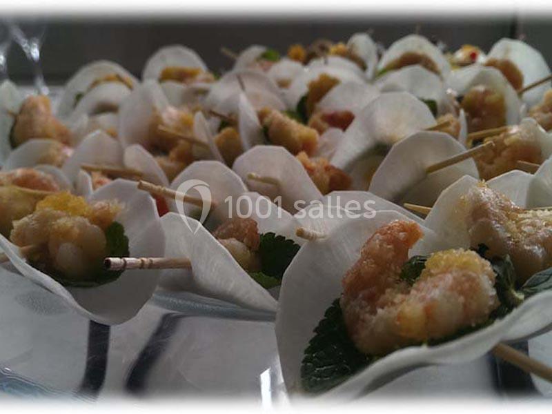 Bouchées apéritives composées de crevettes et d'herbes fraîches, présentées sur des feuilles blanches.
