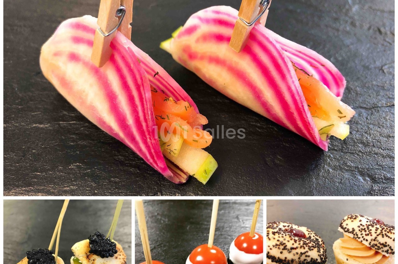 Assortiment de bouchées apéritives élégantes, incluant légumes, brochettes et mini-sandwichs sur ardoise noire.