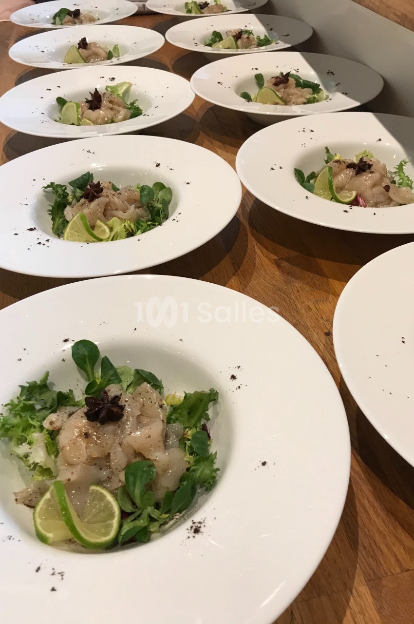 Assiettes de carpaccio de poisson avec salade verte, rondelles de citron vert et étoile de badiane sur une table en bois.