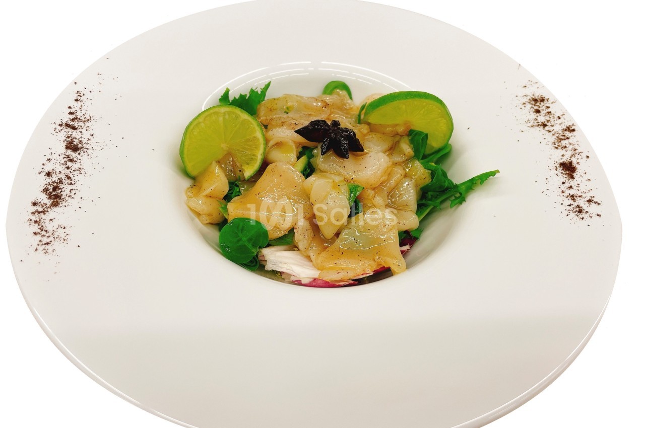 Assiette de carpaccio de Saint-Jacques avec tranches de citron vert, salade verte et décoration de poudre épicée.