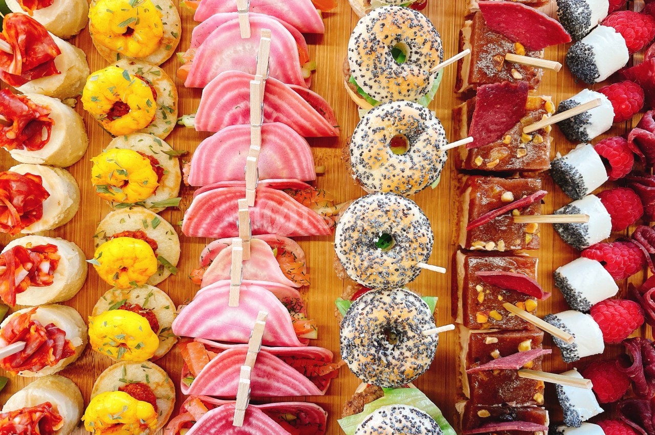 Plateau coloré de bouchées variées : mini-sandwichs, brochettes de fruits et amuse-bouches garnis.